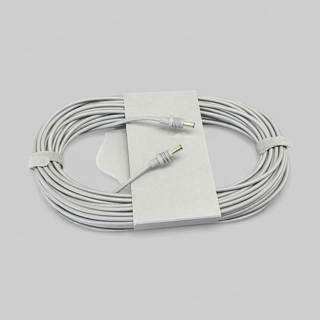 Top-down photo of an Original Starlink 15-meter DC-to-DC cable for the Starlink Mini, coiled and secured with velcro straps, showing both connectors and cardboard holder on a neutral grey background