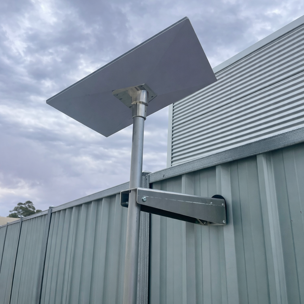 Starlink Gen 3 satellite dish mounted to a corrugated metal fence using a heavy duty aluminium Atco fence mount bracket.